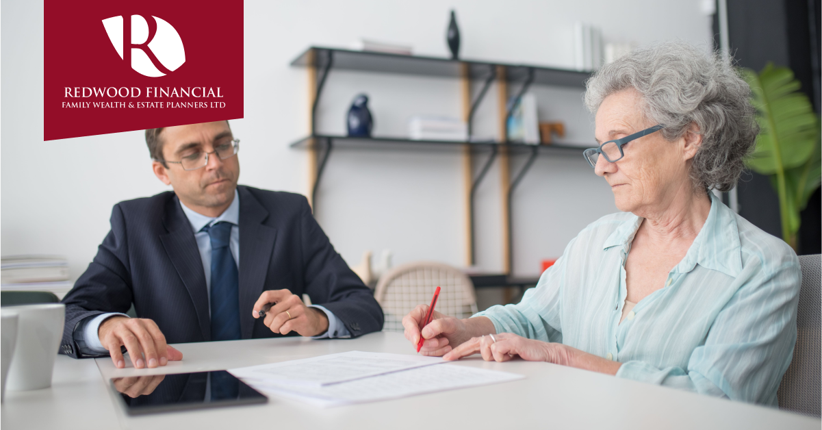Woman sat signing document with man in office